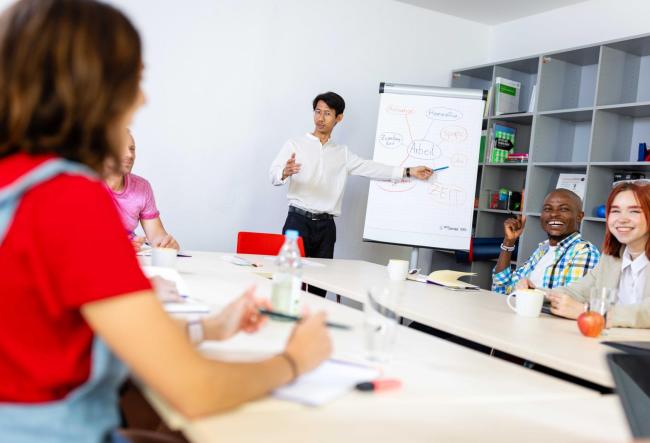 Meeting in a company. The colleagues are discussing something written on the flipchart about work.