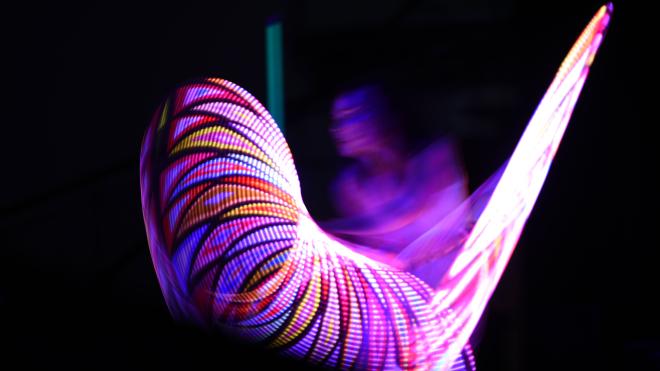 A woman is creating light effects with glowing hulla hoop rings.