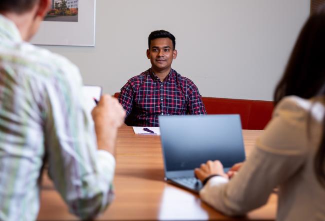 Student being interviewed in a conference room by two faculty members.