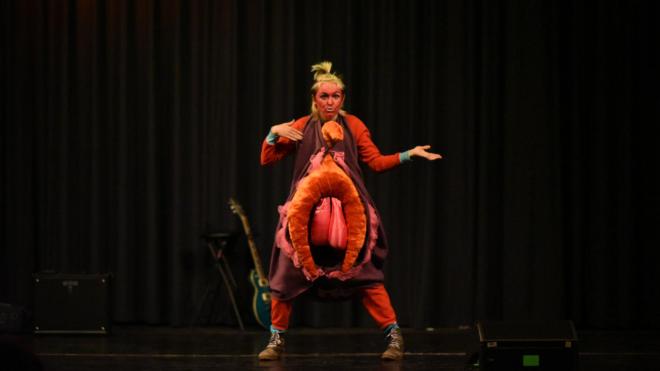 A person in an anatomical costume is seen on stage. They are lip syncing.