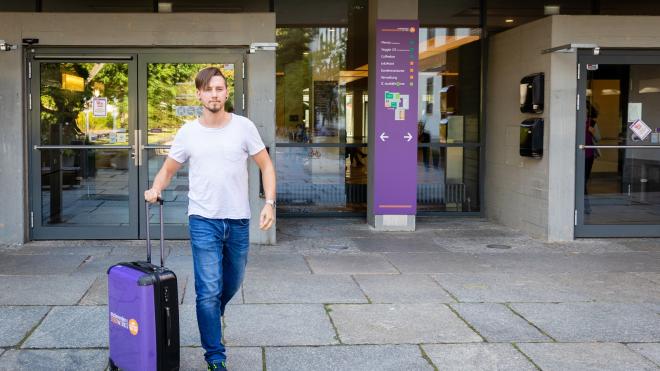 An employee of studierendenWERK leaves the building with an information pack.