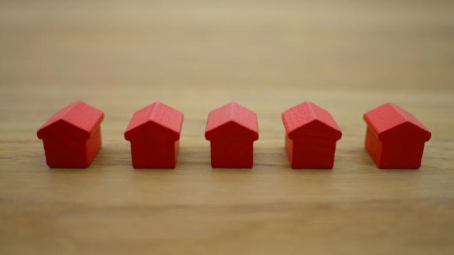 Kleine rote Holzfiguren in Form von Häusern stehen auf einem Tisch