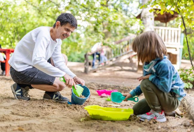 Teacher playing with a child in the sandpit.