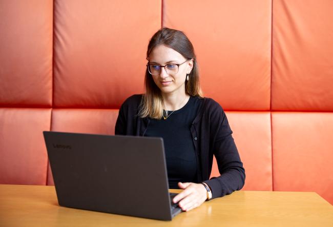 Student at a table, looking down on her Laptopscreen.