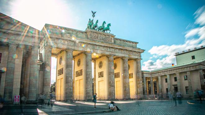 Das Brandenburger Tor wird eindrucksvoll durch Sonne durchstrahlt vor einem blauen Himmel. 