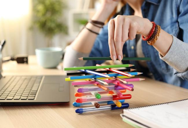 Student sitting in front of her notebook and building a pile of Mikado out of pencils.