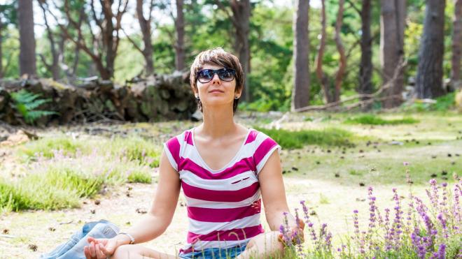 A woman meditates in the forest. 